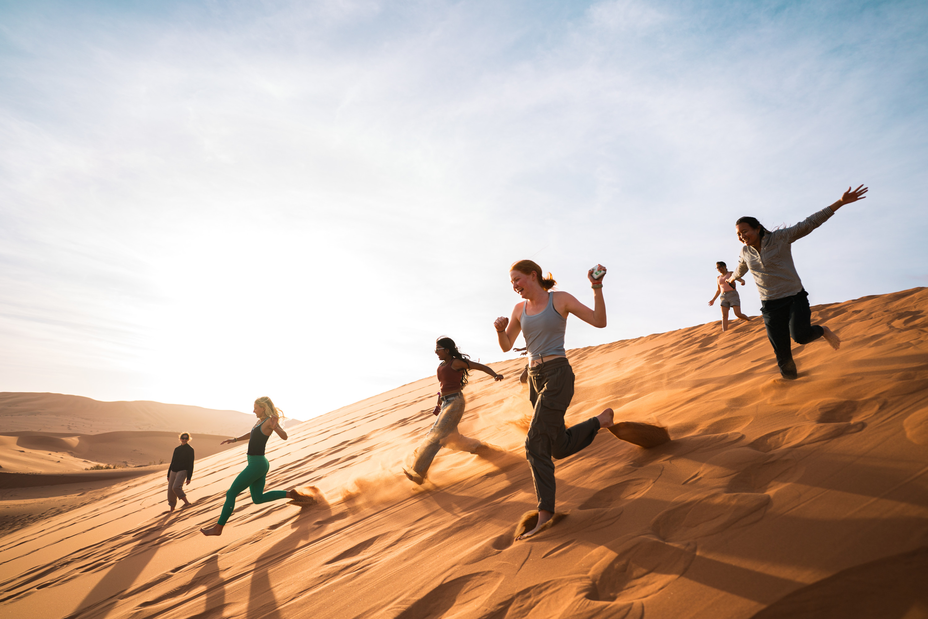 Students run down a sand dune