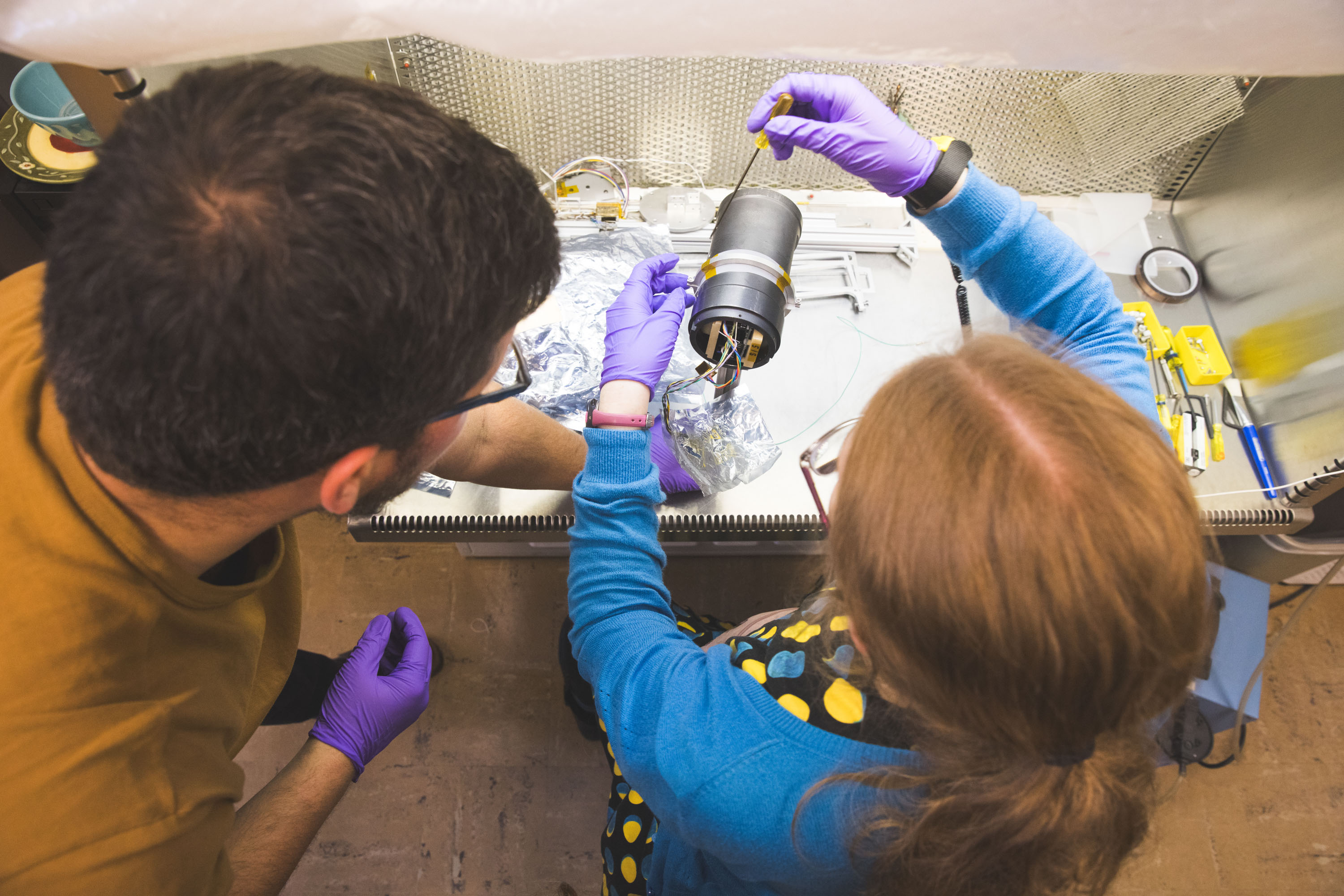 Two people work on a lab instrument